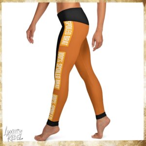 Leggings featuring a bold design with burnt orange and black color blocks, and the text "100% Spoiled Brat" on the side panels. Named Burnt Orange 100% Spoiled Brat Leggings, part of the Luxury Rebel collection.