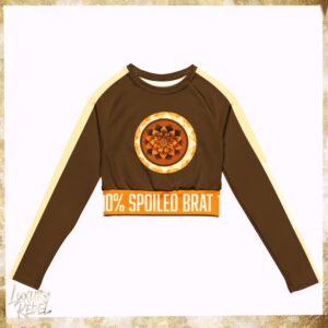 Long-sleeve crop top featuring a golden mandala design on a brown base with cream accents, and the text "100% Spoiled Brat" on the waistband. Named Golden Mandala Luxe Crop Top, part of the Luxury Rebel collection.