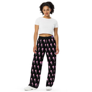 Image of a woman wearing wide-leg pants with an all-over pattern of pink lipstick prints on a black background. She is also wearing a white cropped t-shirt and white sneakers. The pants are loose-fitting and comfortable, combining a playful design with a relaxed fit, perfect for casual wear.