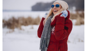 A deep crimson puffer jacket featuring a playful demon-inspired design with white horns, bat wings, and a red bow on the chest. The jacket has a soft padded texture, a zip-up front, and a hood lined with the same patterned crimson fabric. Stylish and warm, it blends sweet and edgy elements seamlessly.