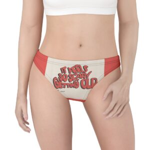 A bold, cream-colored thong with striking red side panels featuring the phrase "It Feels So Scary Getting Old" in retro, bubble-style red lettering.