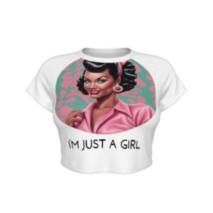 A white cropped t-shirt featuring a large circular graphic of a glamorous Black woman styled in 1950s pin-up fashion. She has glossy black curls, pink earrings, a headband, and a pink collared top. Below the image, the text reads “I’M JUST A GIRL” in bold black letters.