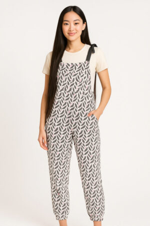 White jumpsuit with black side panels and an all-over pink and black lipstick tube print, featuring adjustable black shoulder ties.